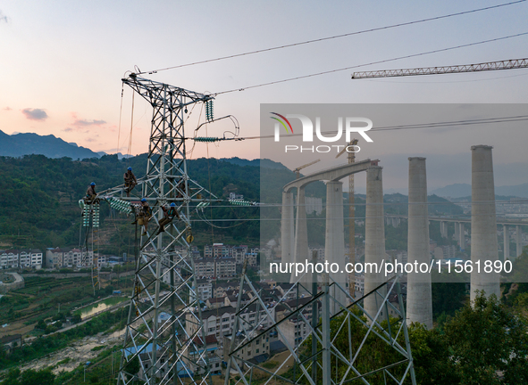 Electric power employees work on a steel tower near the Shuigang Railway in Xikouping village, Yichang city, Central China's Hubei province,...