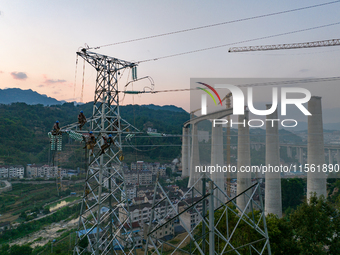 Electric power employees work on a steel tower near the Shuigang Railway in Xikouping village, Yichang city, Central China's Hubei province,...