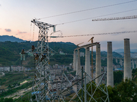 Electric power employees work on a steel tower near the Shuigang Railway in Xikouping village, Yichang city, Central China's Hubei province,...