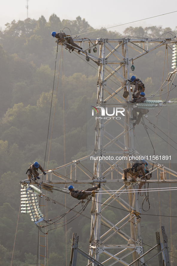 Electric power employees work on a steel tower near the Shuigang Railway in Xikouping village, Yichang city, Central China's Hubei province,...