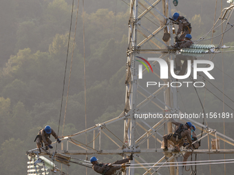 Electric power employees work on a steel tower near the Shuigang Railway in Xikouping village, Yichang city, Central China's Hubei province,...