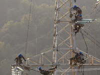 Electric power employees work on a steel tower near the Shuigang Railway in Xikouping village, Yichang city, Central China's Hubei province,...