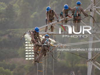 Electric power employees work on a steel tower near the Shuigang Railway in Xikouping village, Yichang city, Central China's Hubei province,...