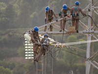 Electric power employees work on a steel tower near the Shuigang Railway in Xikouping village, Yichang city, Central China's Hubei province,...