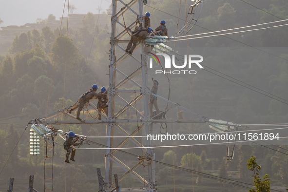 Electric power employees work on a steel tower near the Shuigang Railway in Xikouping village, Yichang city, Central China's Hubei province,...