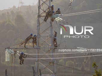 Electric power employees work on a steel tower near the Shuigang Railway in Xikouping village, Yichang city, Central China's Hubei province,...