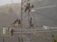 Electric power employees work on a steel tower near the Shuigang Railway in Xikouping village, Yichang city, Central China's Hubei province,...