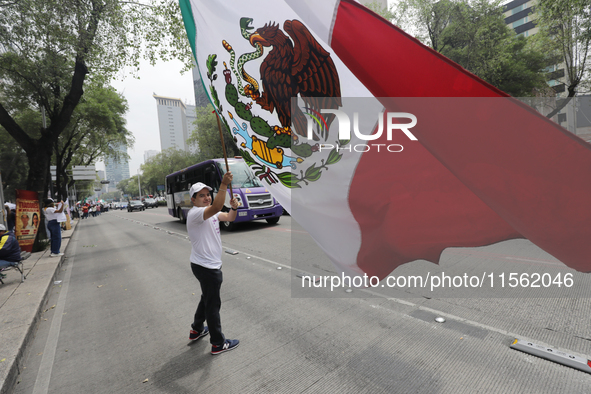 A judiciary worker waves a Mexican flag while taking part in a rally against the judicial reform proposed by current President Andres Manuel...