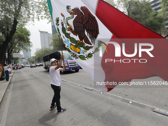 A judiciary worker waves a Mexican flag while taking part in a rally against the judicial reform proposed by current President Andres Manuel...