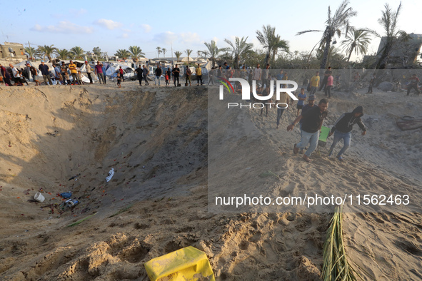 People inspect the site following Israeli strikes on a tent camp sheltering displaced people amid the Israel-Hamas conflict in the Al-Mawasi...