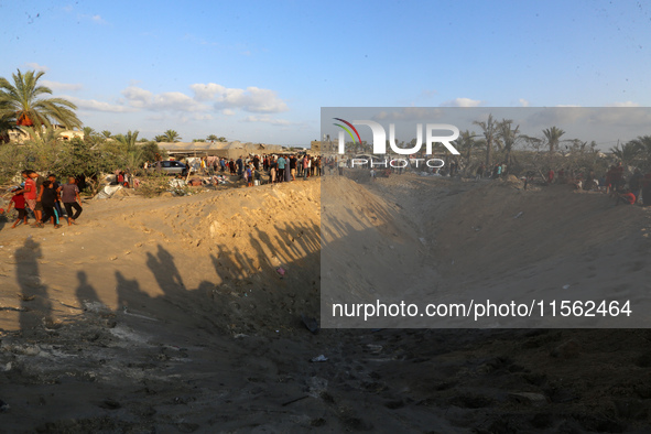 People inspect the site following Israeli strikes on a tent camp sheltering displaced people amid the Israel-Hamas conflict in the Al-Mawasi...