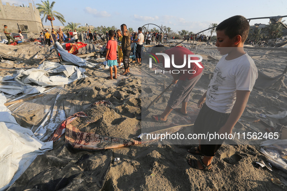 People inspect the site following Israeli strikes on a tent camp sheltering displaced people amid the Israel-Hamas conflict in the Al-Mawasi...