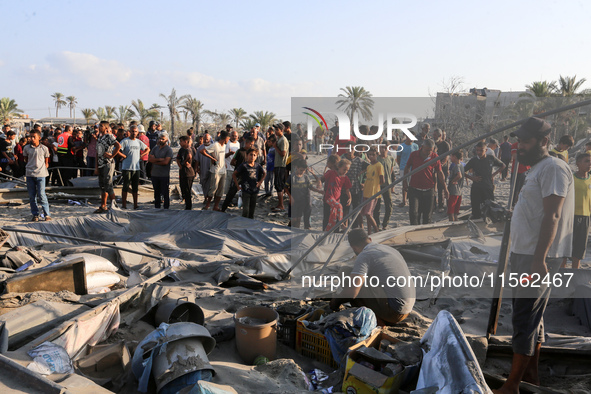 People inspect the site following Israeli strikes on a tent camp sheltering displaced people amid the Israel-Hamas conflict in the Al-Mawasi...