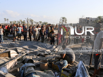 People inspect the site following Israeli strikes on a tent camp sheltering displaced people amid the Israel-Hamas conflict in the Al-Mawasi...