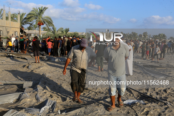 People inspect the site following Israeli strikes on a tent camp sheltering displaced people amid the Israel-Hamas conflict in the Al-Mawasi...