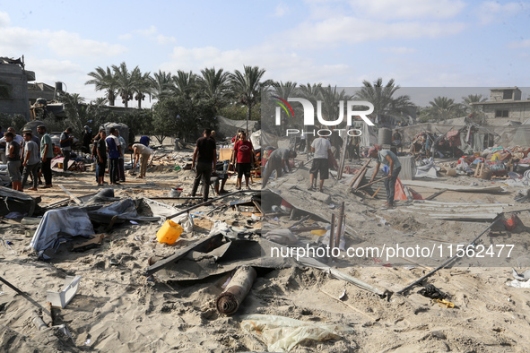 People inspect the site following Israeli strikes on a tent camp sheltering displaced people amid the Israel-Hamas conflict in the Al-Mawasi...