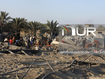 People inspect the site following Israeli strikes on a tent camp sheltering displaced people amid the Israel-Hamas conflict in the Al-Mawasi...