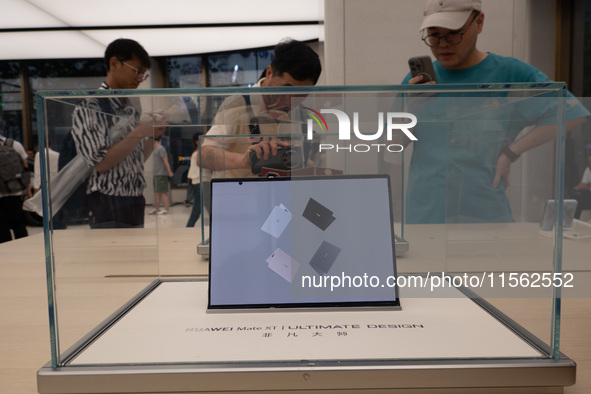 Customers experience the world's first triple foldable screen phone Mate XT just released by Huawei at its flagship store in Shanghai, China...