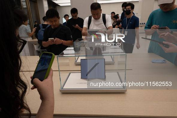 Customers experience the world's first triple foldable screen phone Mate XT just released by Huawei at its flagship store in Shanghai, China...