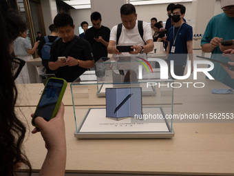 Customers experience the world's first triple foldable screen phone Mate XT just released by Huawei at its flagship store in Shanghai, China...