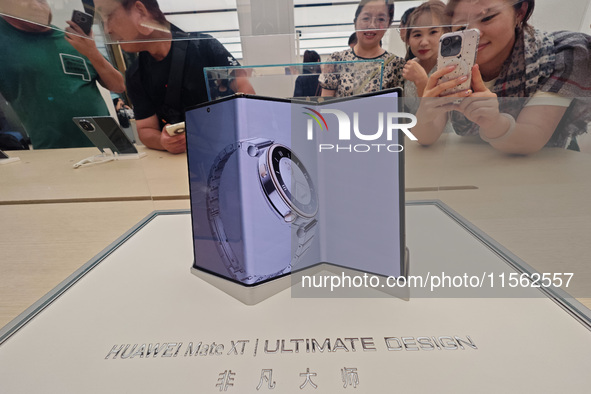 Customers experience the world's first triple foldable screen phone Mate XT just released by Huawei at its flagship store in Shanghai, China...