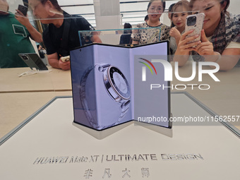 Customers experience the world's first triple foldable screen phone Mate XT just released by Huawei at its flagship store in Shanghai, China...