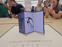 Customers experience the world's first triple foldable screen phone Mate XT just released by Huawei at its flagship store in Shanghai, China...