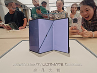 Customers experience the world's first triple foldable screen phone Mate XT just released by Huawei at its flagship store in Shanghai, China...