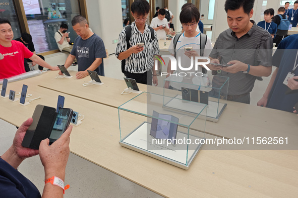 Customers experience the world's first triple foldable screen phone Mate XT just released by Huawei at its flagship store in Shanghai, China...