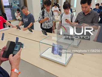 Customers experience the world's first triple foldable screen phone Mate XT just released by Huawei at its flagship store in Shanghai, China...