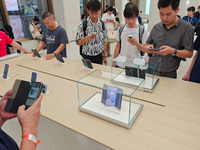 Customers experience the world's first triple foldable screen phone Mate XT just released by Huawei at its flagship store in Shanghai, China...