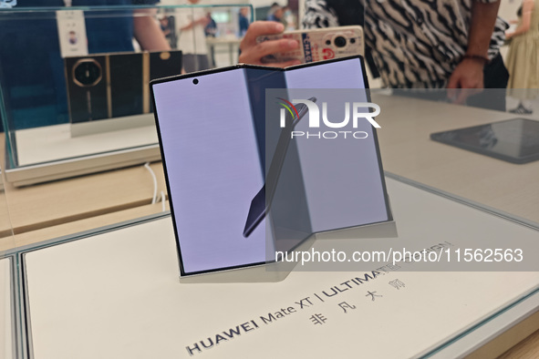 Customers experience the world's first triple foldable screen phone Mate XT just released by Huawei at its flagship store in Shanghai, China...