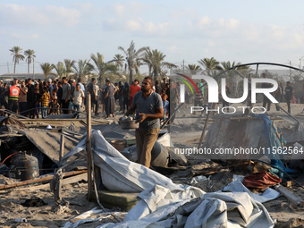 People inspect the site following Israeli strikes on a tent camp sheltering displaced people amid the Israel-Hamas conflict in the Al-Mawasi...