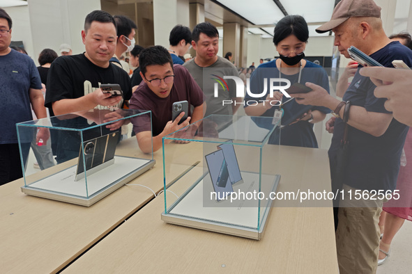 Customers experience the world's first triple foldable screen phone Mate XT just released by Huawei at its flagship store in Shanghai, China...