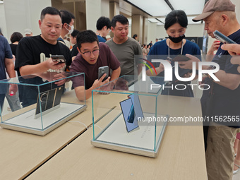 Customers experience the world's first triple foldable screen phone Mate XT just released by Huawei at its flagship store in Shanghai, China...