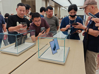 Customers experience the world's first triple foldable screen phone Mate XT just released by Huawei at its flagship store in Shanghai, China...