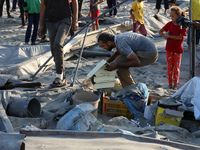 People inspect the site following Israeli strikes on a tent camp sheltering displaced people amid the Israel-Hamas conflict in the Al-Mawasi...