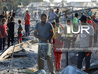 People inspect the site following Israeli strikes on a tent camp sheltering displaced people amid the Israel-Hamas conflict in the Al-Mawasi...