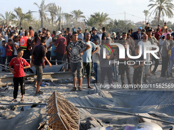 People inspect the site following Israeli strikes on a tent camp sheltering displaced people amid the Israel-Hamas conflict in the Al-Mawasi...