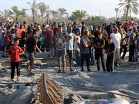 People inspect the site following Israeli strikes on a tent camp sheltering displaced people amid the Israel-Hamas conflict in the Al-Mawasi...