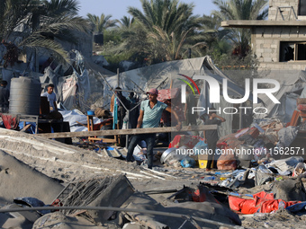 People inspect the site following Israeli strikes on a tent camp sheltering displaced people amid the Israel-Hamas conflict in the Al-Mawasi...