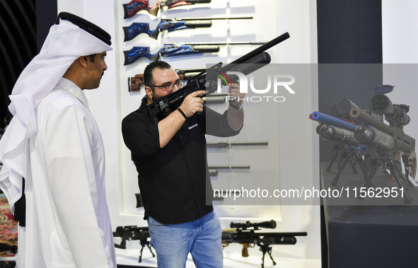 People check a hunting rifle in the guns section at the 8th edition of Katara International Hunting and Falcons Exhibition 2024 (S'hail) at...