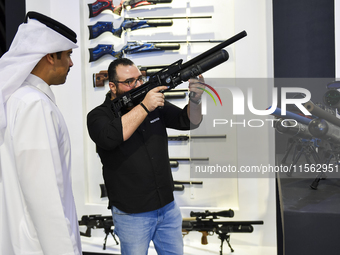 People check a hunting rifle in the guns section at the 8th edition of Katara International Hunting and Falcons Exhibition 2024 (S'hail) at...