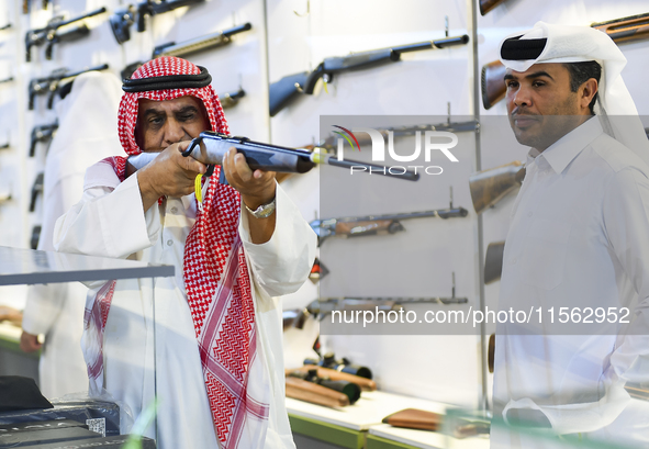 People check a hunting rifle in the guns section at the 8th edition of Katara International Hunting and Falcons Exhibition 2024 (S'hail) at...