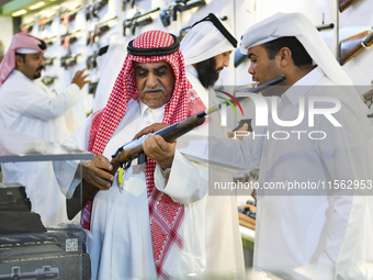 People check a hunting rifle in the guns section at the 8th edition of Katara International Hunting and Falcons Exhibition 2024 (S'hail) at...