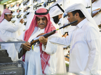 People check a hunting rifle in the guns section at the 8th edition of Katara International Hunting and Falcons Exhibition 2024 (S'hail) at...