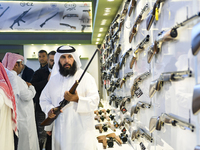 People check a hunting rifle in the guns section at the 8th edition of Katara International Hunting and Falcons Exhibition 2024 (S'hail) at...