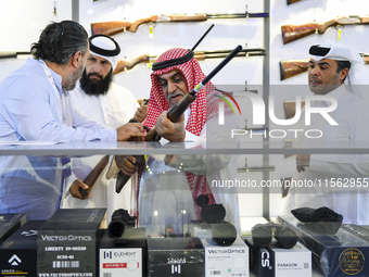 People check a hunting rifle in the guns section at the 8th edition of Katara International Hunting and Falcons Exhibition 2024 (S'hail) at...