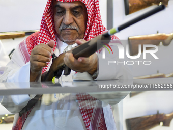 People check a hunting rifle in the guns section at the 8th edition of Katara International Hunting and Falcons Exhibition 2024 (S'hail) at...