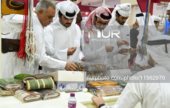 Qatari visitors visit a hunting accessories stall during the 8th edition of the Katara International Hunting and Falcons Exhibition 2024 (S'...